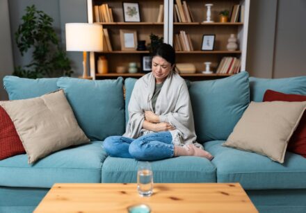 woman sat on a sofa with her feet up clutching her stomach