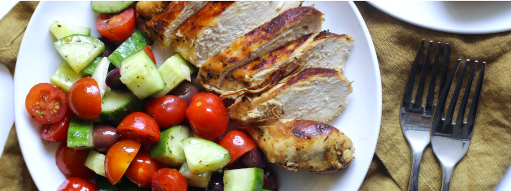 dinner plate with grilled chicken, tomatoes and cucumber